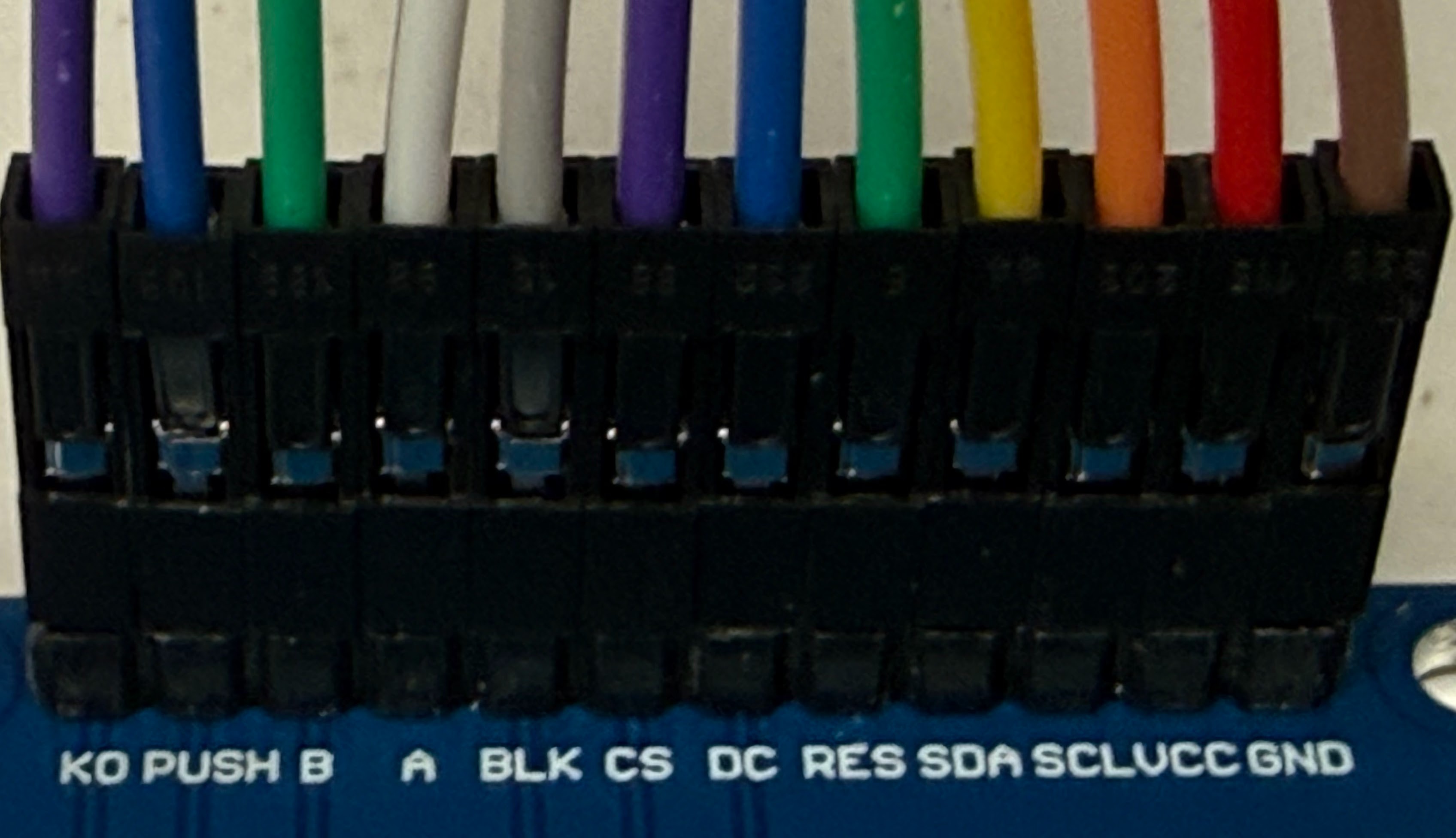 A close-up of the 12 ribbon cable wires plugged onto the display board's pins, with the labels K0, PUSH, B, A, BLK, CS, DC, RES, SDA, SCL, VCC, GND printed below them
